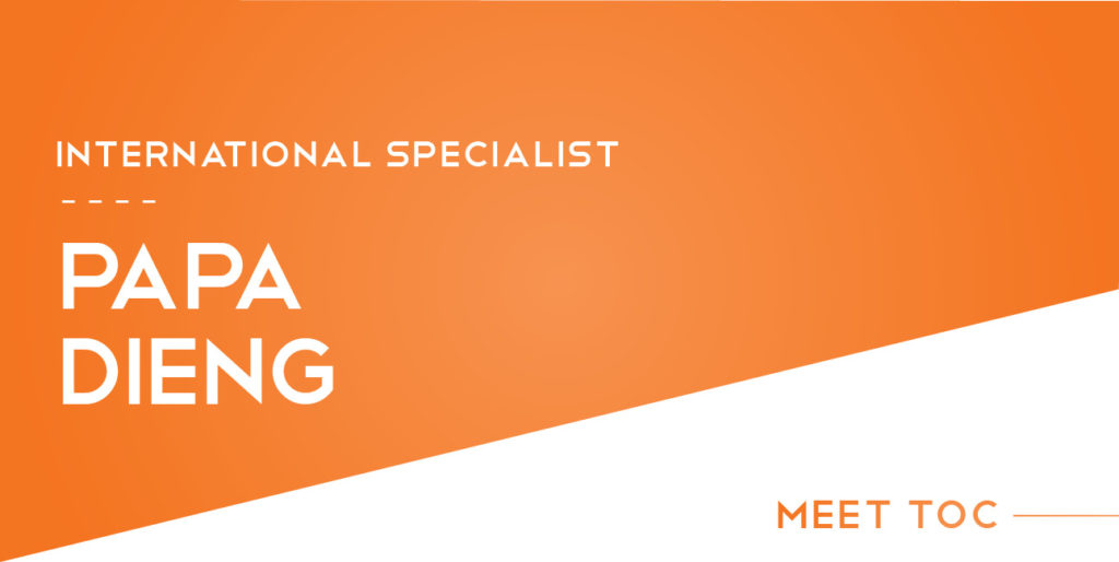 White and orange text on a white and orange geometric background reads, "International Specialist, Papa Dieng. Meet TOC."