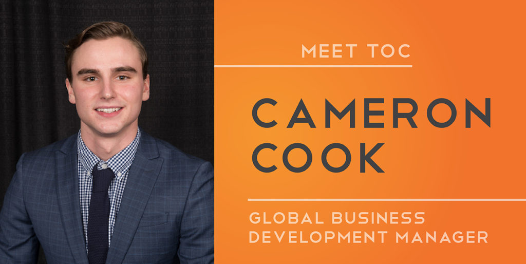 Cameron Cook smiles while wearing a suit. Text next to him reads, "Meet TOC: Cameron Cook: Global Business Development Manager."