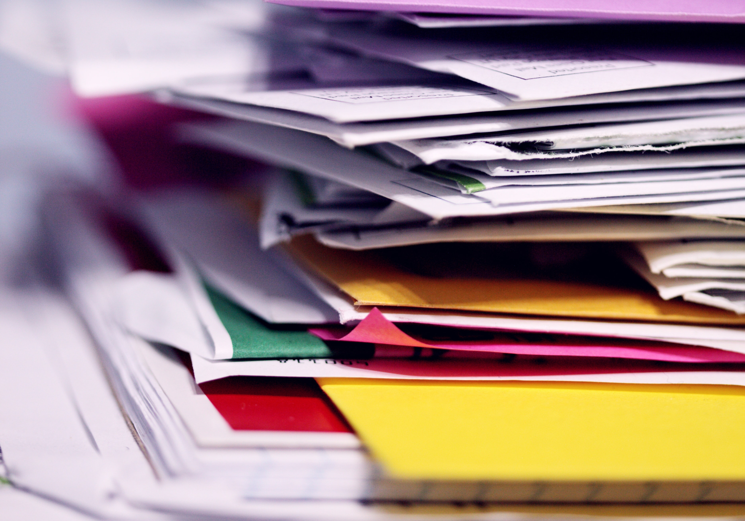 A tall stack of paperwork sits on a table.